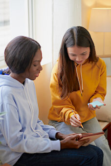 Smiling Multi-ethnic Friends Writing On Sticky Notes When Discussing Video On Tablet Computer | MiddleWeb
